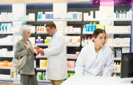 Young female pharmacist looking at display of computer in chemists shopの写真素材