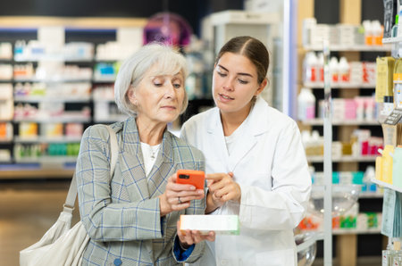 Old woman showing to young female pharmacist QR-code of product on her smartphoneの写真素材