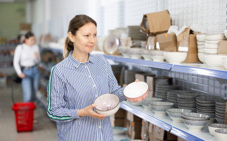 Woman in supermarket is choosing plates with oriental patternの写真素材