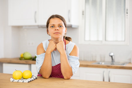 Young housewife in apron posing in modern kitchenの写真素材