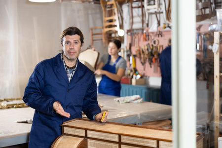 Male furniture workshop worker designing vintage chest of drawers