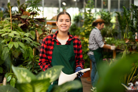 Woman florist withe plastic watering can in floral shopの写真素材