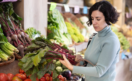 Adult woman chooses beets in vegetable shopの写真素材