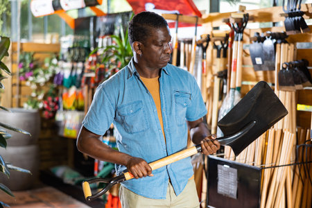 Portrait of african american man choosing shovel in marketの写真素材