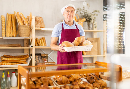 Elderly man with homemade bread in bakeryの写真素材