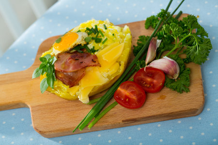Baked potato stuffed with herbs, egg, baconの写真素材