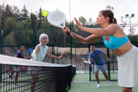 Young woman playing friendly paddleball match on outdoor courtの写真素材