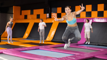 Young woman in sport clothes high jumping in trampoline arena