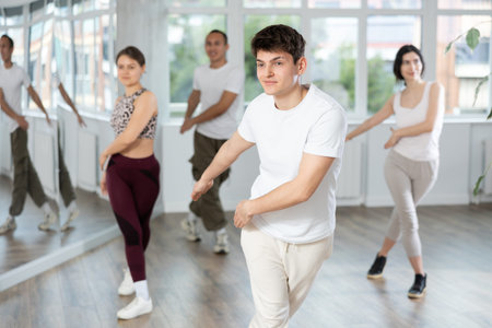 Guy enjoys active dancing, learns new movements, moves synchronously with participants of lesson