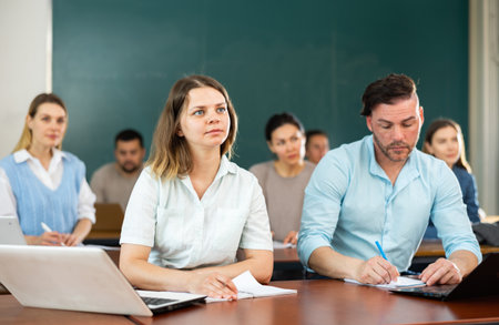 Group of adult students sitting at tables in classroomの写真素材