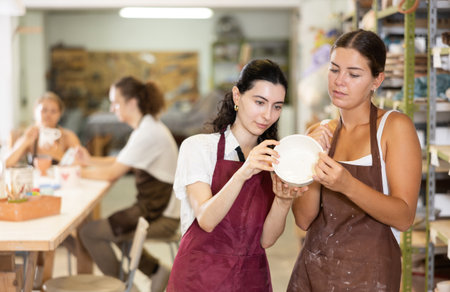 Girl holds ceramic bowl in hands and shows it to friend.の写真素材