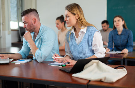 Group of adult students sitting at tables in classroom