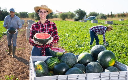 Happy woman farmer with half a watermelon in her hands posing in farmer fieldの写真素材