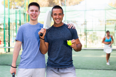 Portrait of satisfied two man with racket and ball in his hands on padel courtの写真素材