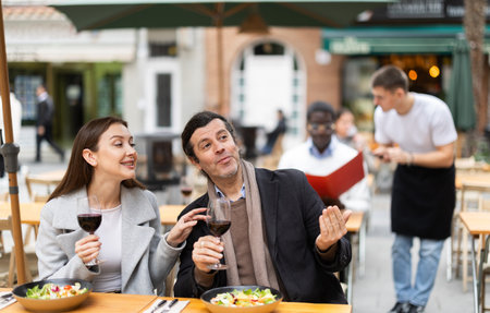 European couple sitting on the terrace of the restaurant and chattingの写真素材