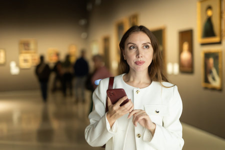 While visiting museum, girl uses travel guide application on her phone.の写真素材