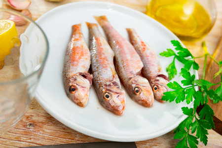 Raw red mullet fish on white plate. Cooking delicious sea fish
