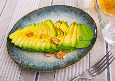 Appetizing avocado and walnuts at table