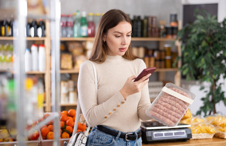 Girl scan QR-code on raw pork sausages in storeの写真素材