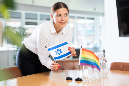 Woman placing flags of Israel and LGBT community on table in office