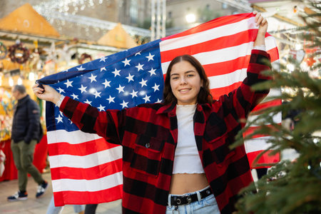 Happy girl with flag of United States at city Christmas market