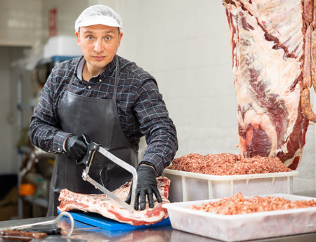 Butcher sawing veal ribs according to customer order
