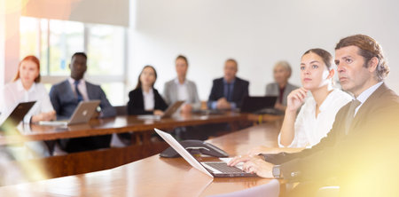 Middle aged white brunette businessman listening to presentation (left side)