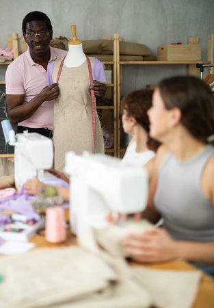 Sewing school teacher conducts lesson for students using mannequin