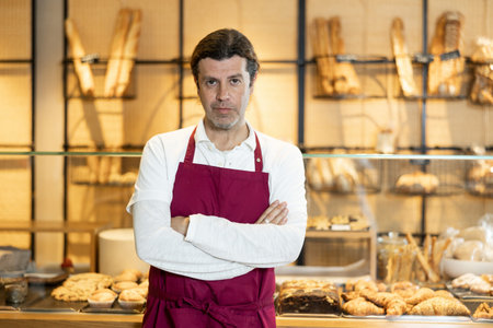 Confident baker in maroon apron posing with arms crossed