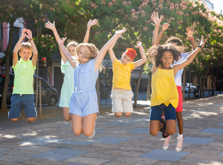 Group of cheerful young girls and boys jumping together