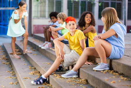Positive tweenagers friendly blabbing while sitting on steps outdoorsの写真素材