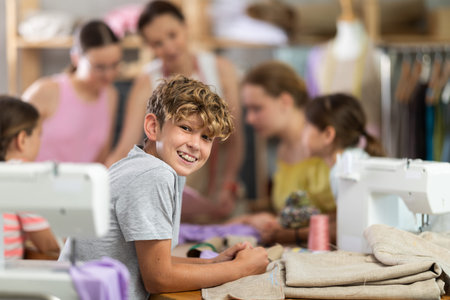 Positive teen boy child in study room of sewing school and young designersの写真素材