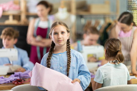Positive teen girl child in study room of sewing school and young designers