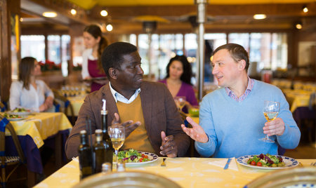 Friendly meeting of two men over dinner in restaurant