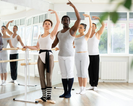 Group mastering third position at barre in ballet studio