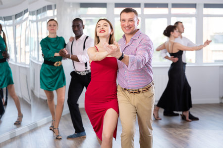 Man and young woman practicing waltz in dancing studio