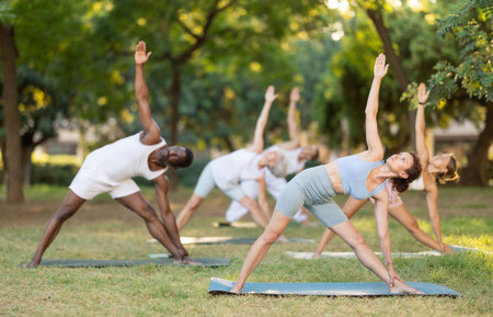 Group pilates and yoga classes in summer park for people of different nationalitiesの写真素材