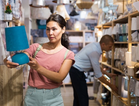 Woman choosing table lamp in storeの写真素材