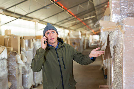 Man in winter clothes talking on mobile phone in warehouseの写真素材