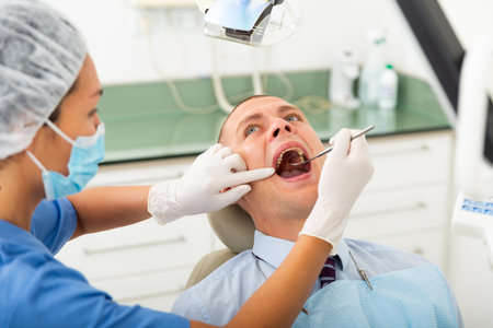 Dentist inspects male patient teethの写真素材