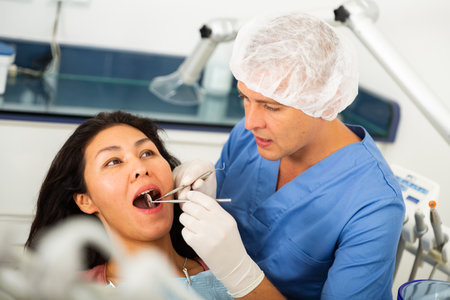 Dentist examining asian female patient teethの写真素材