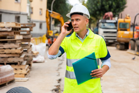 Engineer discussing project by the phone near the buildingの写真素材