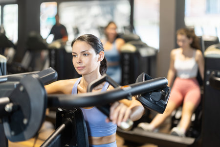 Sportive young girl training on chest press machine in gym