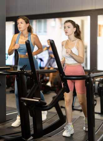 Sportive young women training on treadmill in gym