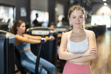 Positive young girl standing in well-equipped gym