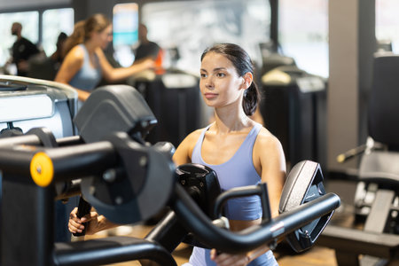 Sportive young girl training on chest press machine in gymの写真素材
