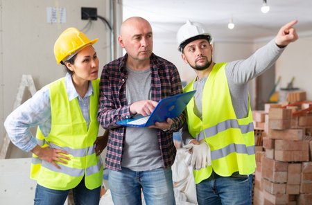 Construction team talking about repair works in apartment and using laptopの写真素材