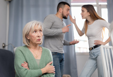 Old woman ignoring her daughter and son-in-law arguing with each otherの写真素材