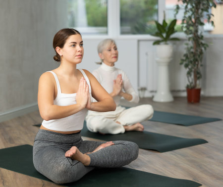 Young woman practicing lotus pose in yoga studioの写真素材