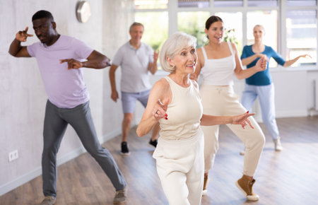 Senior lady dancing twist during group training in dance studio
